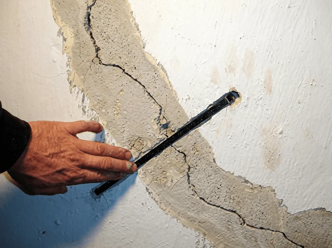 A wall with a large crack is being inspected by a professional in Green Bay, WI